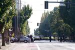 Police officers and cars stand behind crime tape in an image looking south on NE Grand