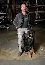 Travis Pond sits with his dog Nova. Pond works out of his Oregon City studio, where he takes pieces of scrap metal and repurposes them into intricate sculpted works.