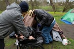 FILE - A volunteer holds on to a wheelchair as they help Max Hartfelt into his tent after relocating him from one park to another on Saturday, March 23, 2024, in Grants Pass, Ore.