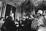President Lyndon B. Johnson extends a hand to shake hands with Martin Luther King Jr. while others watch at the U.S. Capitol in 1965.