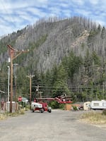 A telescopic boom lift navigates downtown Blue River, which still bears the scars of the 2020 Holiday Farm Fire.