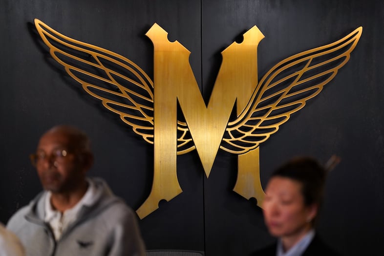The Multnomah Athletic Club emblem decorates the wall as club president Daniel Williams and trustee Julie Kim listen during a press conference in the MAC hallway.