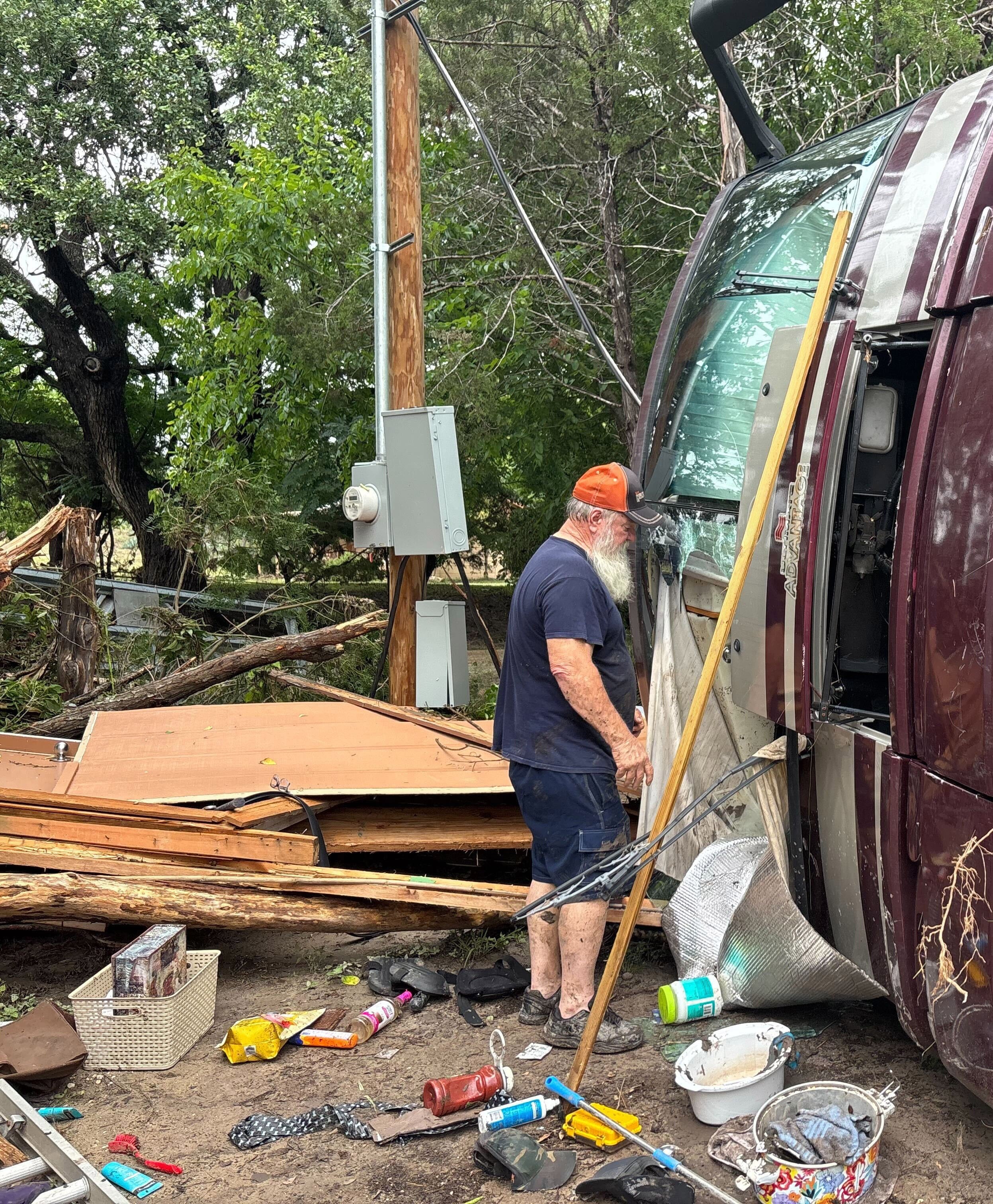 Melvin Harris, 65, cleans up around his motor home, which was flipped by the violent waters of the Guadalupe River in Kerrville, Texas.