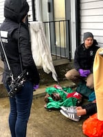 In this February 12, 2019, photo, two CAHOOTS workers talk to a homeless woman near Eugene's west side. They took her to a church for shelter and a meal.