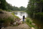 Chris Hughes, Assistant Water/Wastewater Operator for the towns of Cavendish and Proctorsville, VT , walks near where water is discharged into part of the Black Rivier.