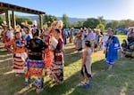Groups of Nez Perce tribal members and descendants gather in circles to talk in some grass.