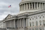 A white stone building with columns and a US flag flying outside.