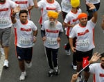 Centenarian marathon runner Fauja Singh, then aged 101, center, runs in a 10-kilometer race, held as part of the annual Hong Kong Marathon, in Hong Kong in 2013.