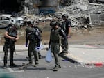 Israeli police retrieve weapons used by militants outside a police station that was overrun by Hamas gunmen on Saturday, in Sderot, Israel, Sunday, Oct.8, 2023. Hamas militants stormed over the border fence Saturday, killing hundreds of Israelis in surrounding communities.