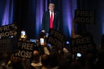 People hold up signs reading "Free Ross" as Donald Trump arrives to address the Libertarian National Convention in Washington, D.C, on May 25, 2024. Ross Ulbricht, the founder of the online marketplace Silk Road, was sentenced to life in prison in 2015.