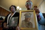 Sisters Barbara Leak-Watkins, right, and Alberta Lynn Fantroy pose with photos of their late father, Alex Leak Jr., at Watkins' home in Greensboro, N.C., on Wednesday, Nov. 4, 2020. The Army veteran died in July after collapsing from dehydration at his assisted-living facility, and the family believes pandemic-related neglect is to blame. As more than 90,000 of America?s long-term care residents have died in a coronavirus pandemic that has pushed staffs to the limit, advocates for the elderly say a tandem wave of death separate from the virus has quietly claimed thousands more, often because overburdened workers haven?t been able to give them the care they need. (AP Photo/Allen G. Breed)