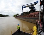 A worker watches a crane unload scrap metal along the Tennessee-Tombigbee Waterway in Columbus, Miss., in 2019. While the waterway hasn’t lived up to expectations in terms of traffic or economic development in parts of Alabama and Mississippi, cities including Columbus rely on it for jobs and transportation.