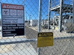 A gate and signs stand guard at one of the Hanford site’s tank farms.