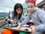 Elise Cha, left, and Kellee Kendrick, right, learn about the viscosity of magma by pouring corn syrup on cookie sheets.