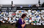 In this May 28, 2020, file photo, a woman passes a fence outside Brooklyn's Green-Wood Cemetery adorned with tributes to victims of COVID-19 in New York.