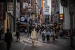 A man wearing a face mask walks along a shopping street on March 25, 2022 in Tokyo, Japan.