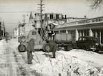 Crew by trucks and scoopmobile for snow removal on SW 12th Ave between Main and Jefferson Streets, SW Portland, Feb. 2, 1950. The First Baptist Church can be seen on the right side in the distance. 