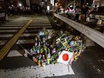 A Japanese national flag is placed next to flowers at a site outside of Yamato-Saidaiji Station where Japan's former Prime Minister Shinzo Abe was shot on Friday in Nara, Japan.