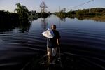 Jean Chatelier walks down a street flooded by Hurricane Irma after retrieving his uniform from his house so he could return to work at a supermarket in Fort Myers, Fla., on Sept. 12, 2017.