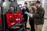 A group of students stand around a piece of machinery.