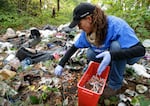 FILE - In this Nov. 8, 2017 file photo, a volunteer outreach worker with an addiction and homeless advocacy group cleans up needles used for drug injection that were found at a homeless encampment in Everett, Wash. 