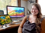 Eugene artist Liza Mana Burns sits next to a digital version of her "Celebrate Oregon!" mural. Burns designed "Celebrate Oregon!" as a special edition license plate, and recreated the piece into four large murals.