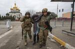 Ukrainian servicemen help an elderly woman, in the town of Irpin, Ukraine, Sunday, March 6, 2022. With the Kremlin's rhetoric growing fiercer and a reprieve from fighting dissolving, Russian troops continued to shell encircled cities and the number of Ukrainians forced from their country grew to over 1.4 million.