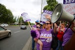 Kaiser Permanente dental assistant Lisa Pharmeter waves at cars honking in support of union members who are rallying for higher pay and more jobs in Vancouver, Wash., on Tuesday, July 23, 2019.