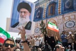 Demonstrators wave Iranian flags as one holds up a poster of Iran's Supreme Leader Ayatollah Ali Khamenei during a protest against Israeli attacks on Iran, after the Friday prayer ceremonies on June 20, 2025 in central Tehran, Iran.