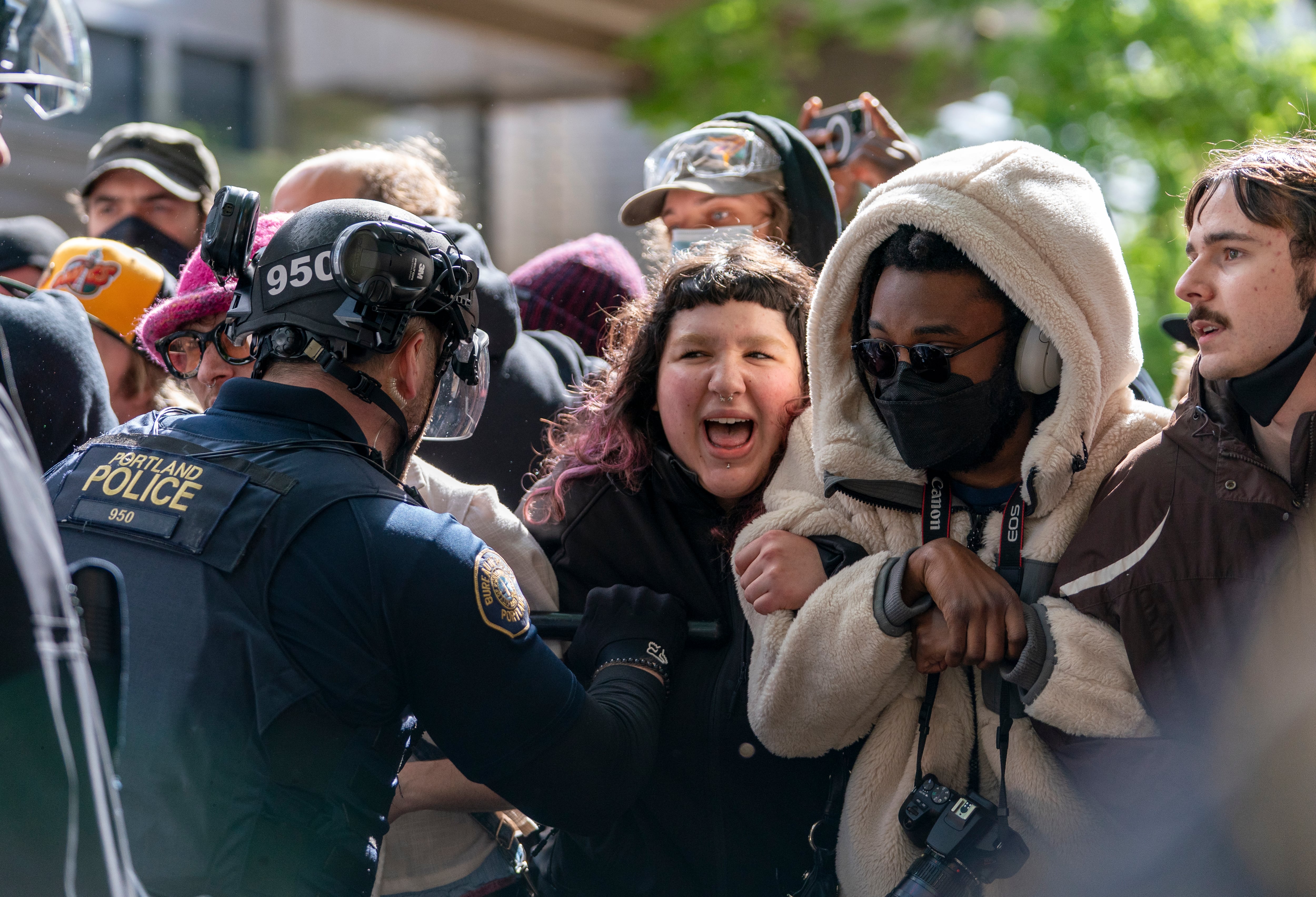 People attempt to stop a white van carrying protesters detained by police at Portland State University's Branford Price Millar Library, May 2, 2024. People protesting Israel's role in the war in Gaza had occupied the library since Monday evening.