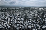 TOPSHOT - This aerial photograph, taken on October 2, 2023, shows the Rusayo IDP camp, home to tens of thousands of war-displaced people, located at the foot of the active Nyiragongo volcano, on the outskirts of Goma in the East of the Democratic Republic of Congo. Since mid-2022, hundreds of thousands of Congolese have found refuge around Goma after fleeing fighting further north between the Congolese army and the Rwandan-backed M23 rebellion. Every month, over 2,000 women are treated in IDP camps all around the city by Doctors Without Borders (MSF) after being sexually assaulted, mostly by "armed men" while trying to find food in the surrounding forests and fields.