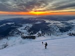 The sun rises over the Central Cascades as the roped-up adventurers ascend to the summit of Mount Rainier in late May.