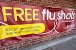 This photo shows a wide banner advertising free flu shots. It hangs on a brick wall.