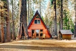 An A-frame house surrounded by large trees.