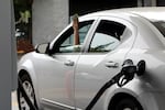 A driver holds cash out of the window of their car while waiting to pay a gas station attendant to pump their gas, Friday, Aug. 4, 2023, in Portland, Ore.