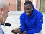 Tim Weah smiles as he talks to his dad, George, on a cell phone during his interview with NPR's Tom Goldman. "Make sure your jersey is wet and dirty," George told his son.