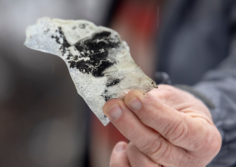 Jay Hennigan, president of the Breitenbush Cabin Owners Association, holds up a piece of melted glass where his cabin once stood in Breitenbush, March 5, 2021. The area was destroyed by the Beachie Creek and Lionshead fires in 2020.