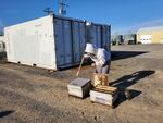 In this photo released by Washington State University, a beekeeping scientist prepares a queen bee bank near the refrigerators where the banks were stored.