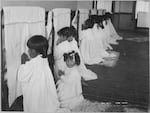 Students pray beside their beds at an Indian boarding school in Arizona, around 1900.
