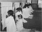 Students pray beside their beds at an Indian boarding school in Arizona, around 1900.