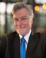 Portrait of a man with a suit and blue tie.