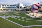 A large U.S. flag in memory of Charlie Kirk hangs on the side of a building on the campus of Utah Valley University in Orem, Utah, on September 19, 2025. The flag faces a terraced, grassy green space.
