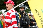 Portland police watch as a Proud Boys rally continues under the Hawthorne Bridge in Portland, Ore., Saturday, Aug. 17, 2019. The Proud Boys espouse white supremacist ideology and have been designated a hate group by the Southern Poverty Law Center.