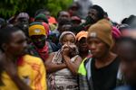 Residents watch an excavator remove rubble from a collapsed building three days after a 7.2 magnitude quake in Les Cayes, Haiti, Tuesday, Aug. 17, 2021, the day after Tropical Storm Grace swept the area.