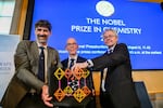 From left, Chair of the Nobel Committee for Chemistry Heiner Linke, Secretary General of the Swedish Academy of Sciences Hans Ellegren, and Member of the Nobel Committee for Chemistry Olof Ramstrom pose Wednesday after announcing Susumu Kitagawa, Richard Robson and Omar Yaghi as the recipients the Nobel Prize in Chemistry, at the Nobel Assembly of the Karolinska Institutet, in Stockholm, Sweden.