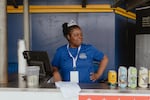 Melody, concessions worker at Robin Roberts Stadium, awaits her first customers on Opening Day of the Women's Pro Baseball League. Springfield, IL, August 1, 2026.