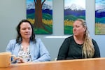 Erin Lair, left, is talking talking at a table while Toni Myers is seated next to her and listening.