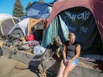 Rena, a person experiencing homelessness in Bend, sits in front of her tent with her dog, Scooby, in October, 2022. 