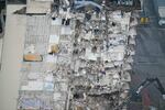 An aerial view of a building with major damage and a crane in the foreground.