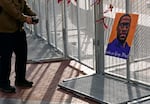 A passerby stops to take a photo of a George Floyd picture hanging on the fence surrounding the Hennepin County Government Center in Minneapolis where the trial for former Minneapolis police officer Derek Chauvin continues on Friday, April 2, 2021. Chauvin is charged with murder in the death of George Floyd during an arrest last May in Minneapolis.